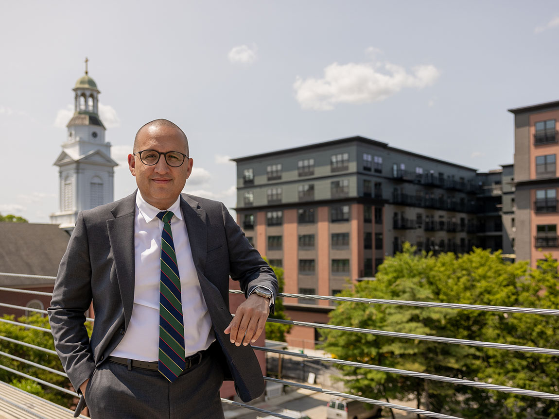 A man in a suit stands in front of a city skyline